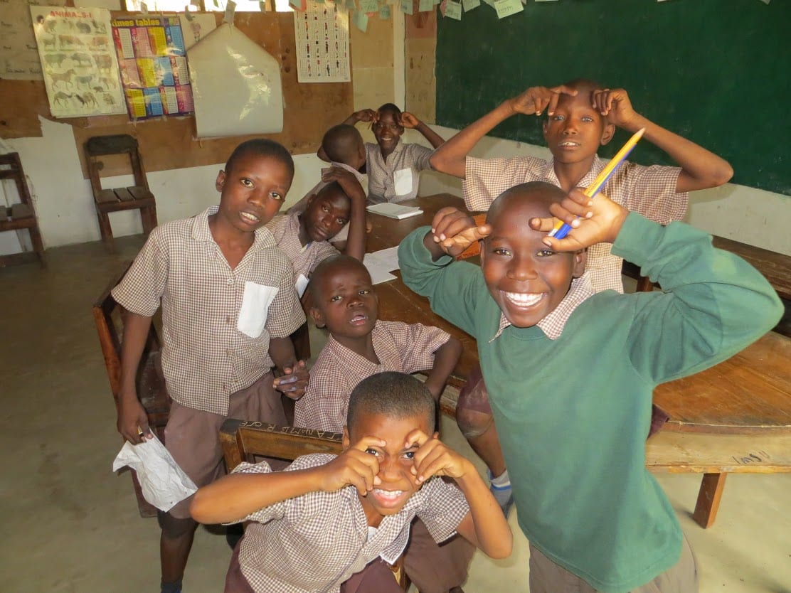 Eight Kenyan school boys in a classroom, smiling.