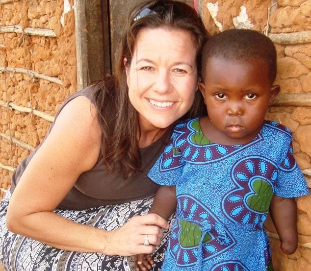 An adult female standing beside a Kenyan girl who is missing her left hand.