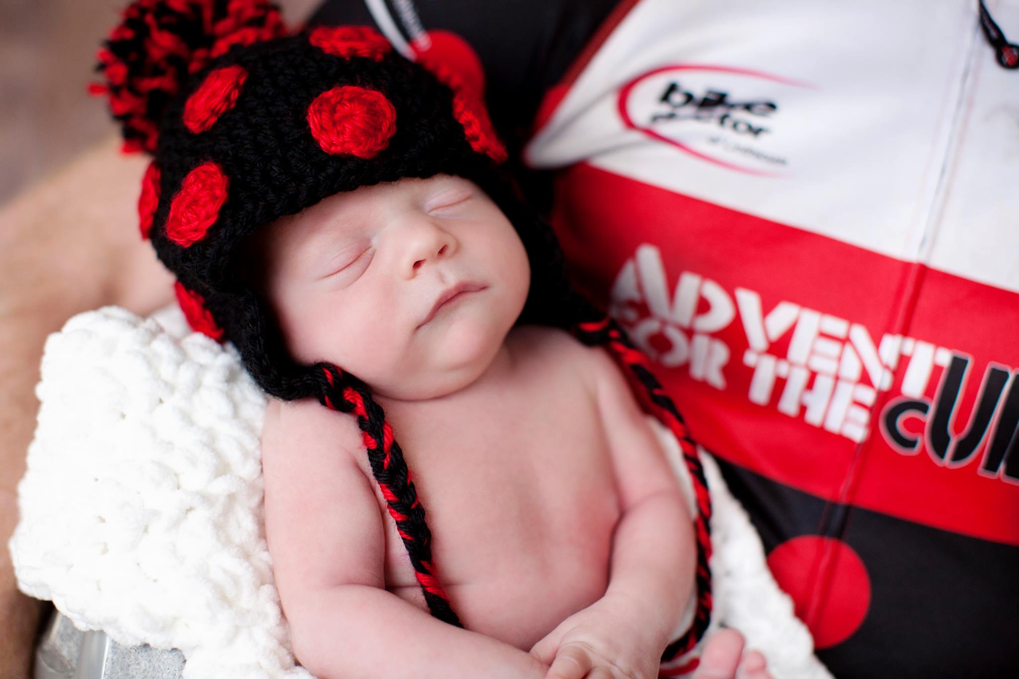 A very young baby wearing a black and red knitted hat.