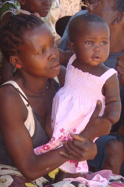 A Kenyan woman holding a young girl who is missing her left hand.