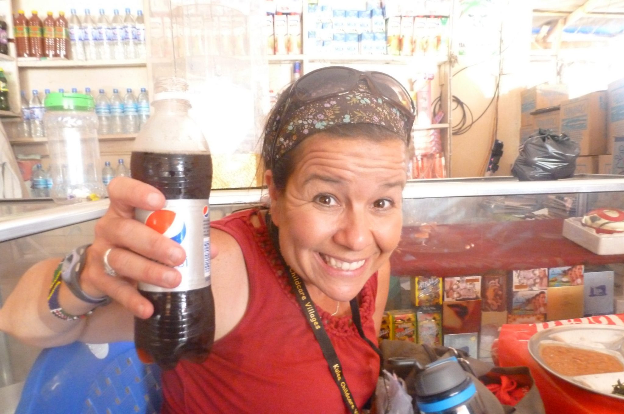 An adult woman smiling, holding a bottle of soda.