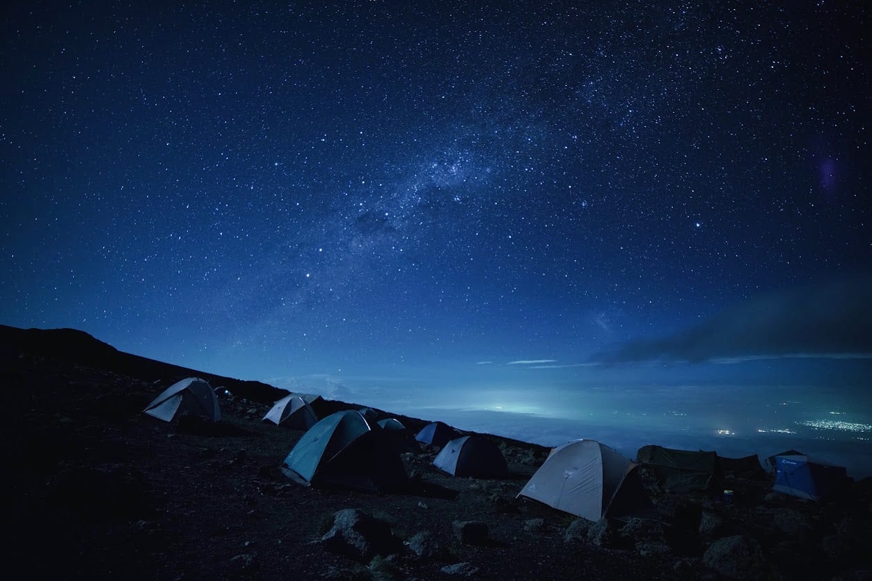 Several tents spread out under the night sky covered with stars.