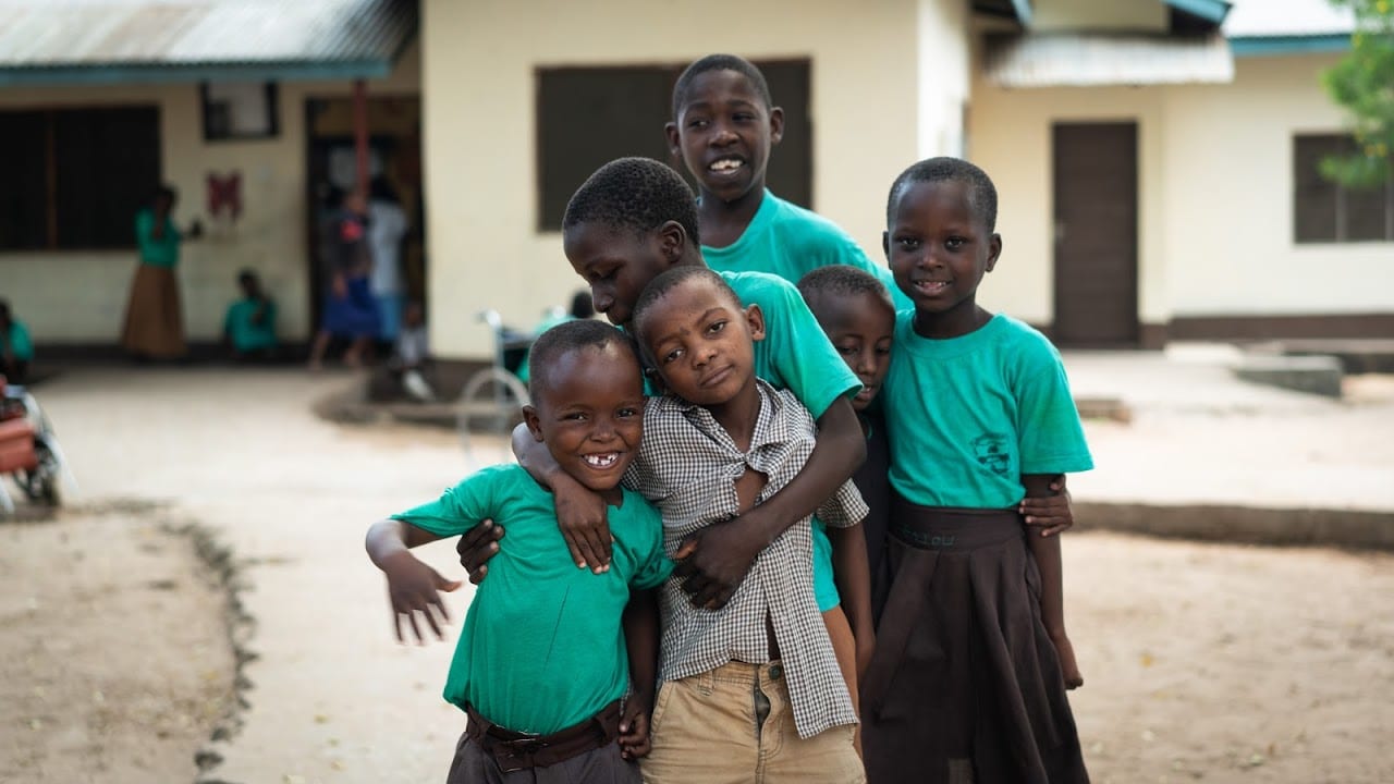 Six Kenyan boys hugging and smiling at the camera.