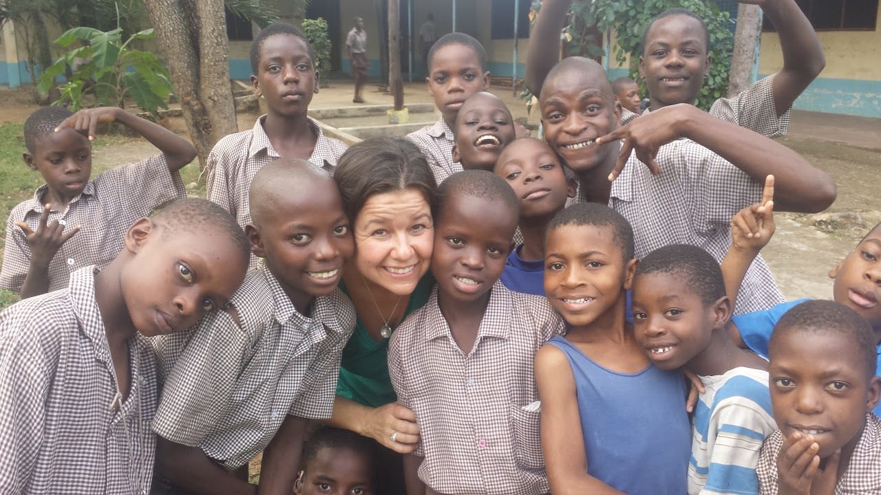 Cynthia Bauer smiling, surrounded by a group of smiling young boys.