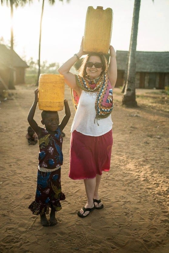 An American woman holding a container above her head standing beside a young child who also has a container