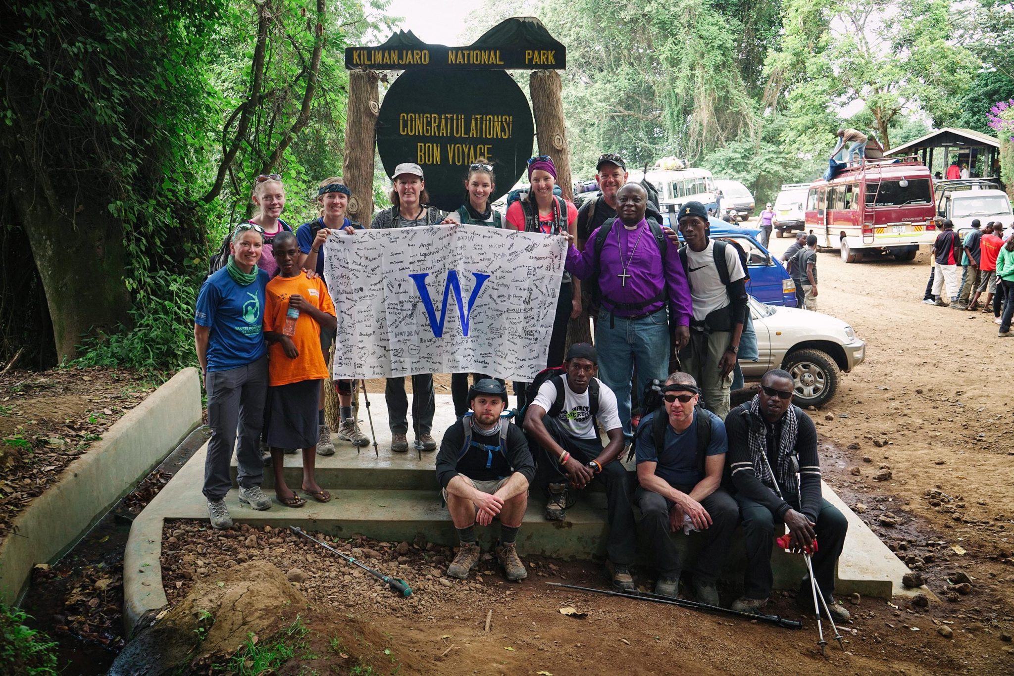 14 hikers standing together and holding a banner with a large "W" in the center.