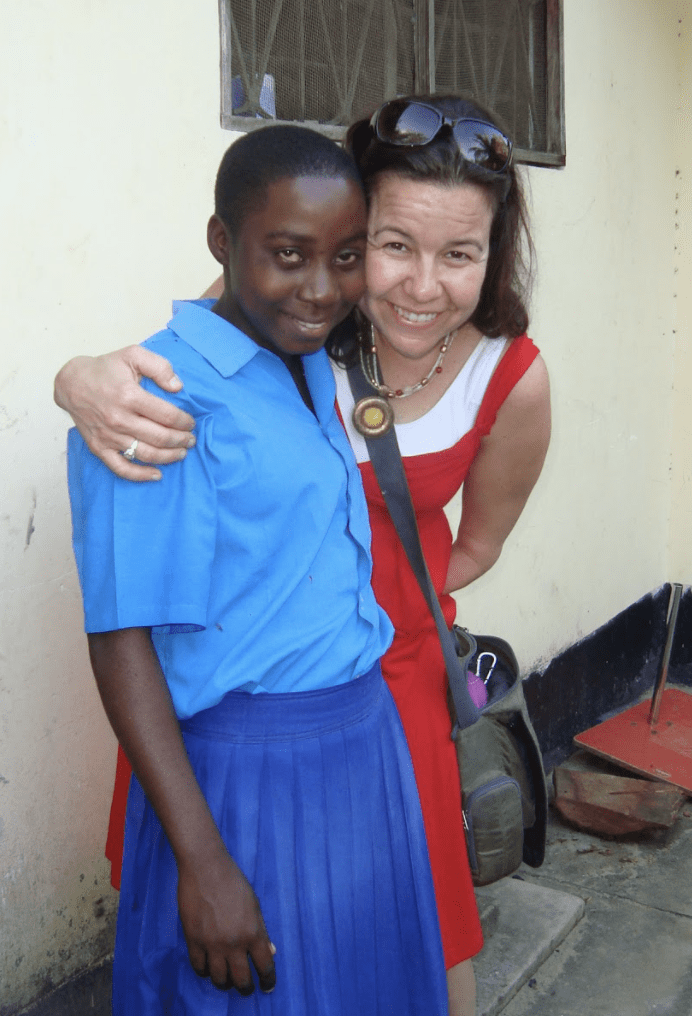 An adult woman with her arm around a Kenyan schoolgirl.