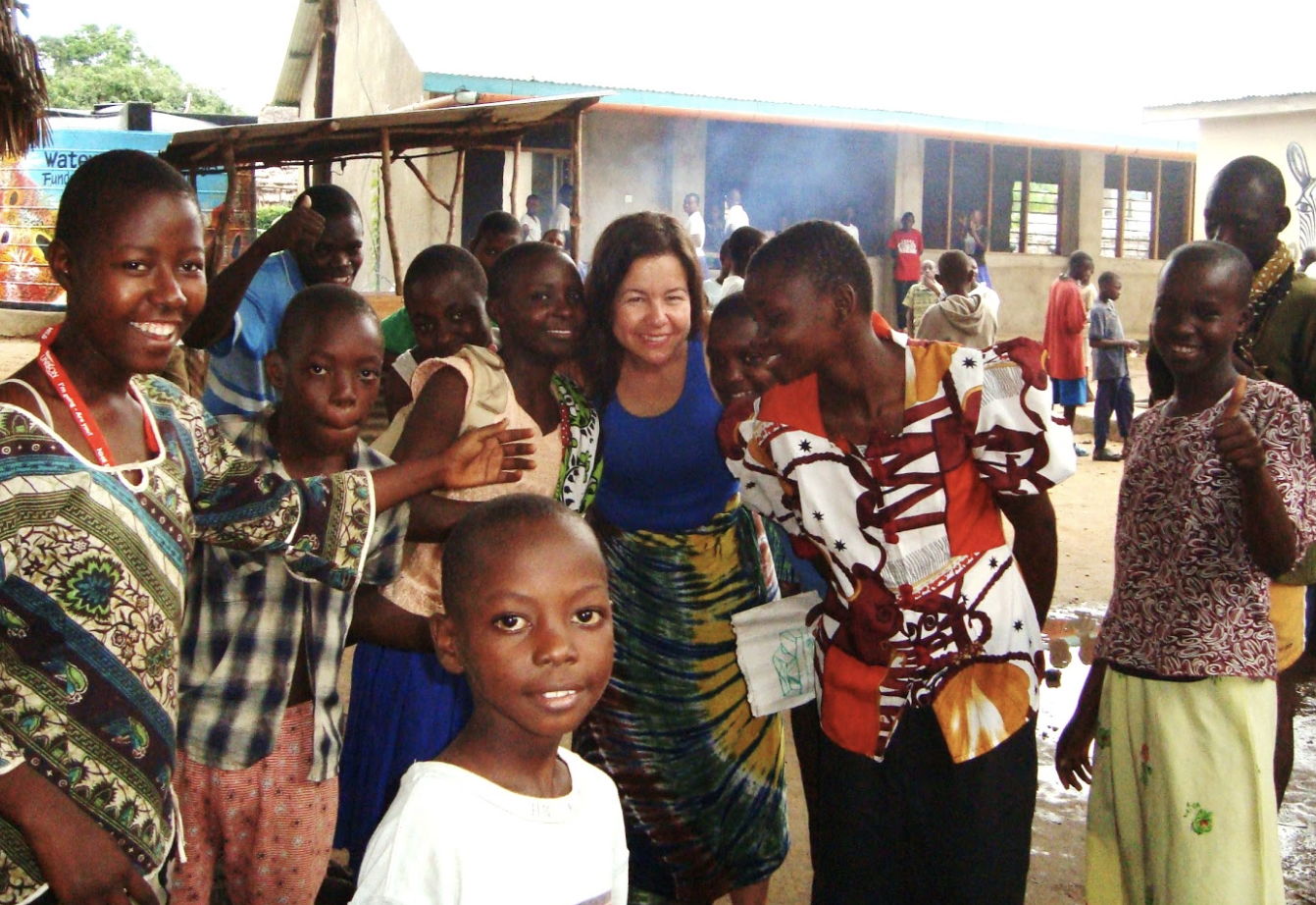 An adult woman surrouded by 10 Kenyan teens.