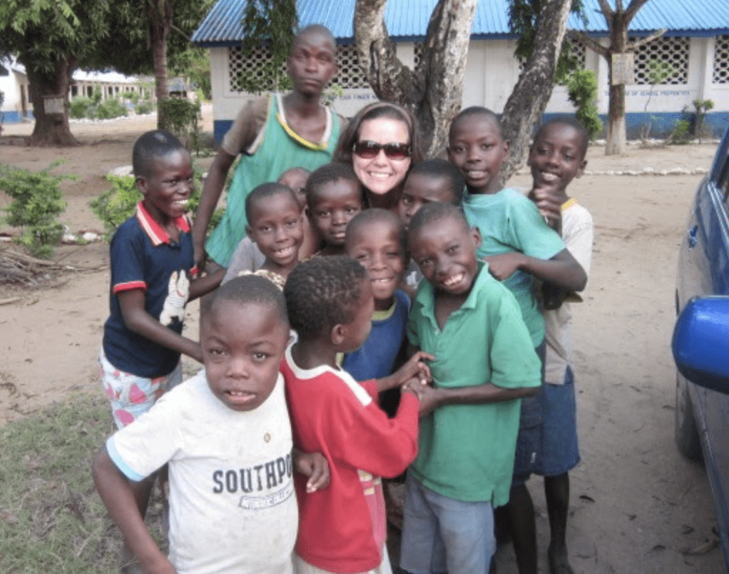 An adult female standing with 12 Kenyan children.