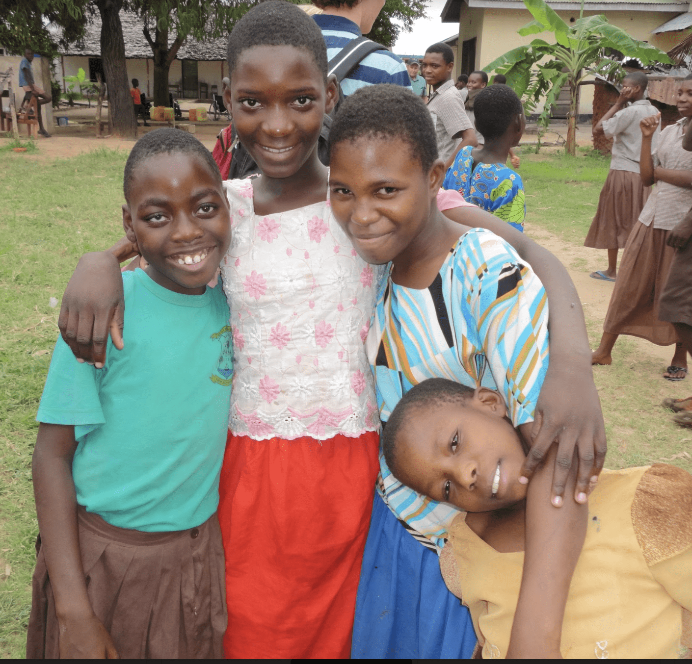 Four Kenyan children standing together and smiling.