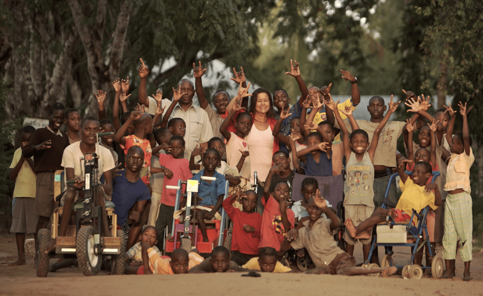 38 children and two adults holding their hands in the air.