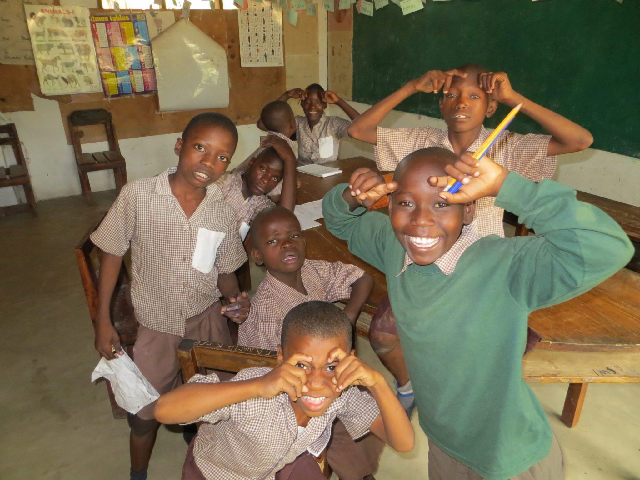 A group of 8 Kenyan school boys who are in a classroom.