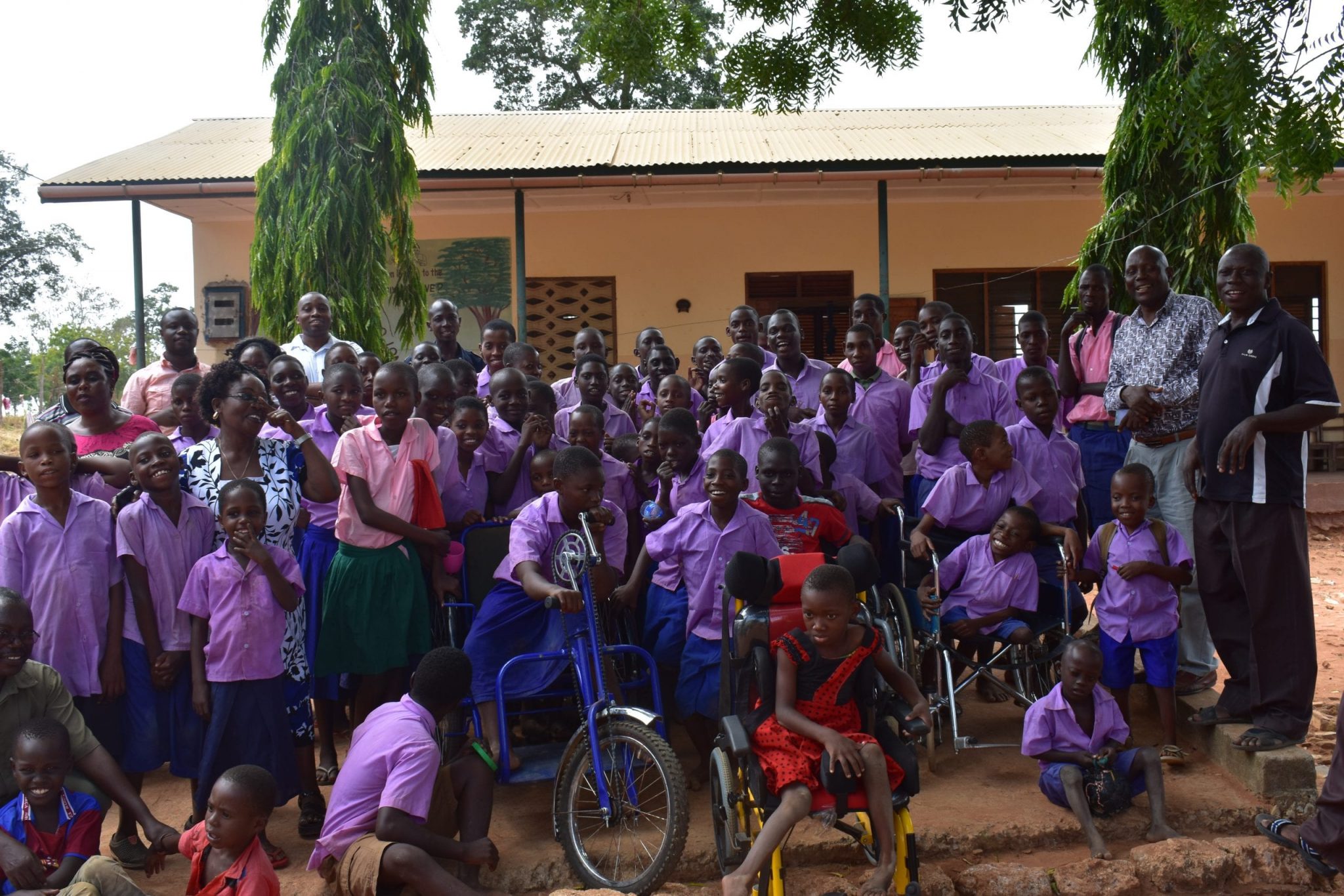 A large group of Kenyan students all wearing light purple shirts.