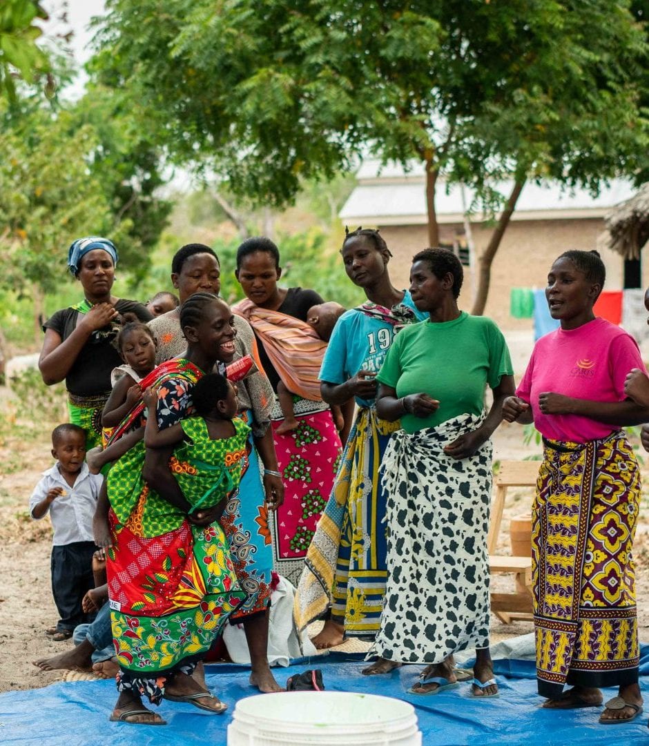 A group of 7 Kenyan women and 4 children all standing together outside.