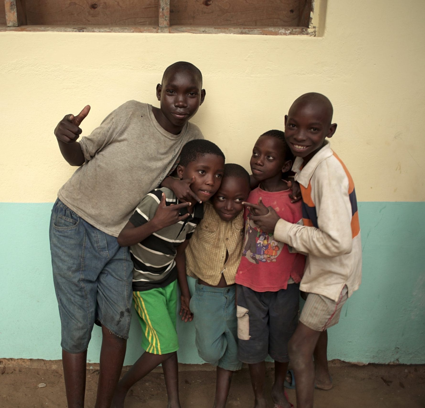 Five Kenyan children standing outside of a building together.