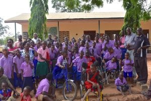 A large group of Kenyan children sitting outside of a building.