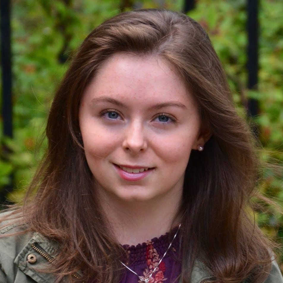 Mikayla Martin headshot- smiling with background of green forestry.