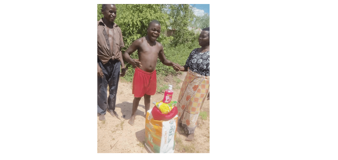 Child smiling with two adults after receiving Kupenda food relief.