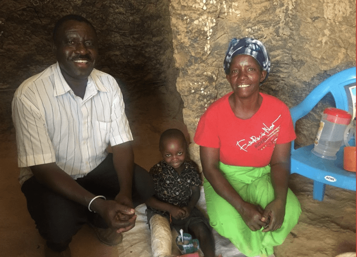 Kenyan parents with small child smiling and sitting together.