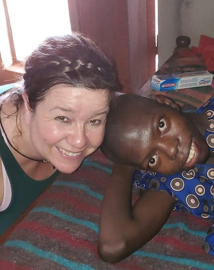 An adult woman smiling beside a Kenyan young woman.