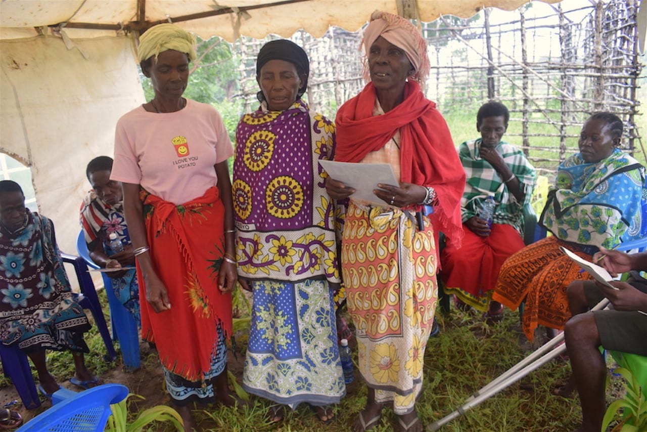 Three women standing within a circle of listening women