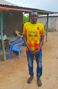 Kenyan boy in a vibrant yellow shirt standing outside