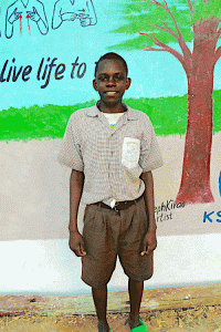 Kenyan boy standing in front of a mural on a building