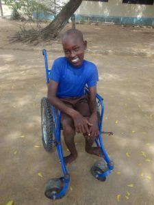 A young boy wearing a blue shirt, seated in a wheelchair