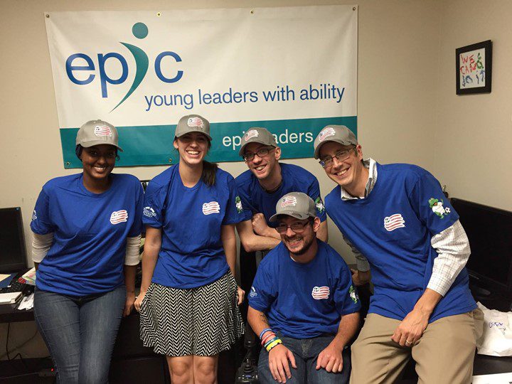 Five individuals wearing matching blue shirts, smiling. 