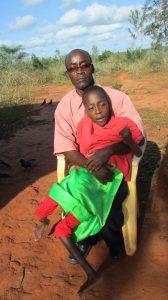 Father has son on lap in chair.