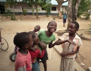 A group of children laughing with each other near a school in Kenya