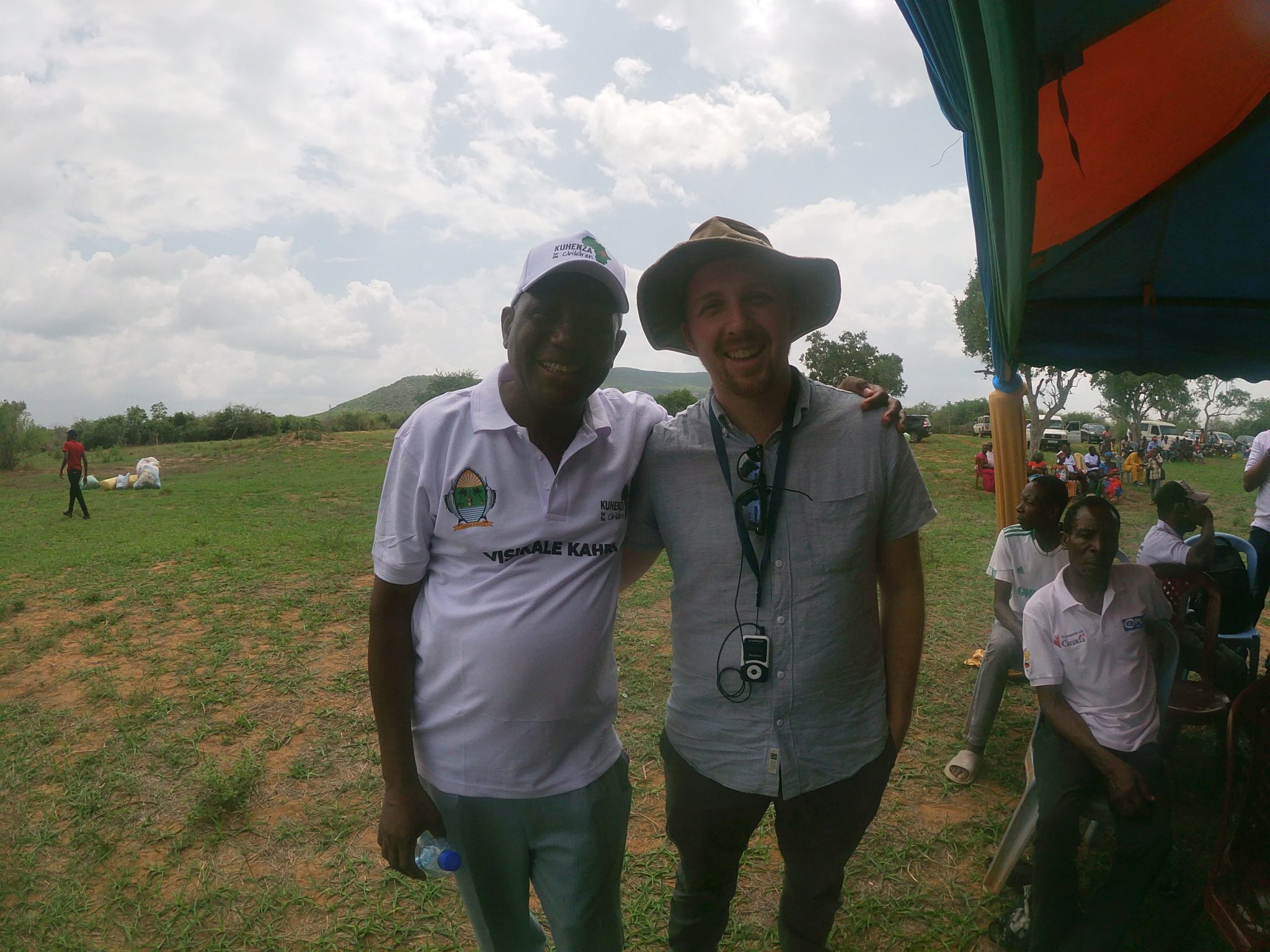 A group of two standing together in a rural setting, smiling at the camera.