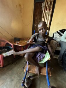A young kenyan boy in a wheelchair in his home