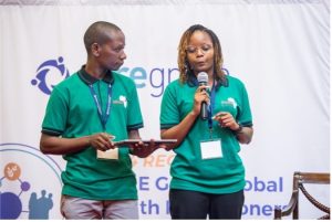 A man and a woman wearing matching green shirts, presenting at a conference.