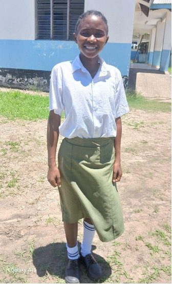 Young girl in school uniform with white collared shirt and a long green skirt