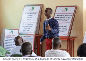 George shares his testimony during a disability advocacy workshop for Christian leaders in Kenya, with disability and faith discussion materials displayed behind him